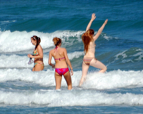 Three young girls playing in sea waves.