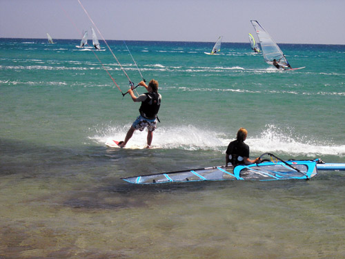 Image of two young people performing the activity of windsurfing during their holidays in Greece.